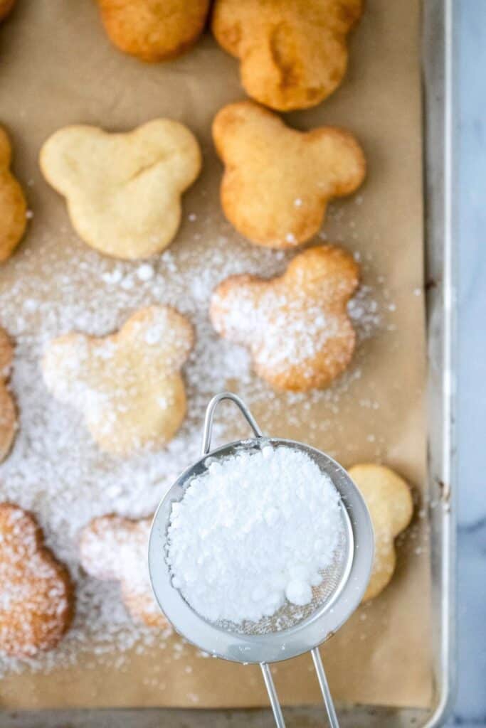 adding a dusting of powdered sugar to gluten free beignets